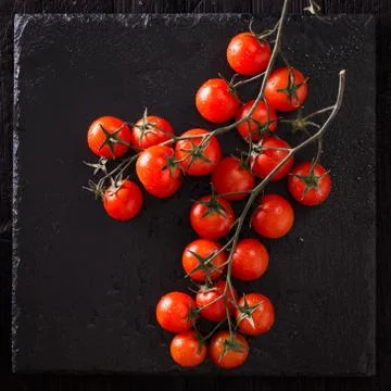 Small red cherry tomatoes on an old dark wooden table in rustic style Stock Photos