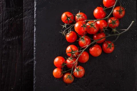 Small red cherry tomatoes on an old dark wooden table in rustic style Stock Photos