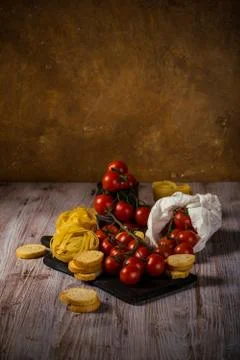 Small red cherry tomatoes on several twigs with tagliatelle Stock Photos