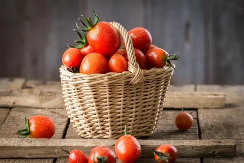 Small red cherry tomatoes  in a small wicker basket Stock Photos