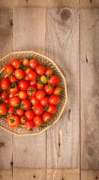 Small red cherry tomatoes  in a wicker basket Stock Photos