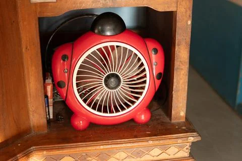 A small red children's model sitting fan is placed in a cupboard Stock Photos