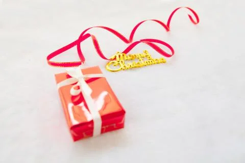 Small red gift box and gold merry christmas text with red ribbon Foto stock
