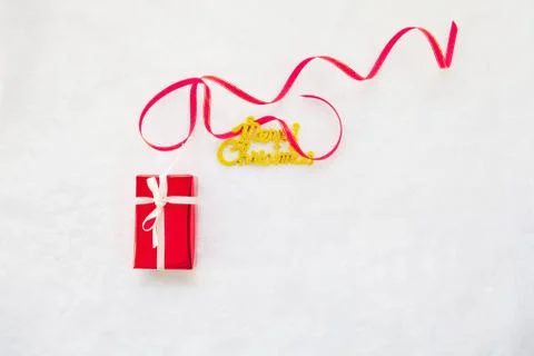 Small red gift box and gold merry christmas text with red ribbon Foto stock