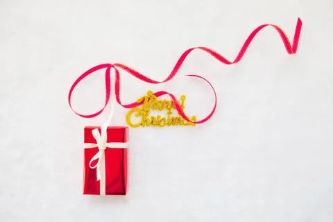 Small red gift box and gold merry christmas text with red ribbon Foto stock