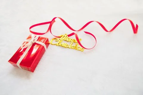Small red gift box and gold merry christmas text with red ribbon Stock Photos