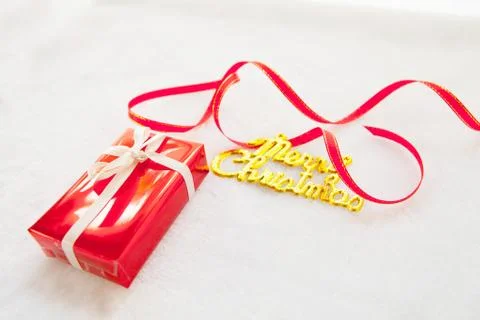 Small red gift box and gold merry christmas text with red ribbon Stock Photos
