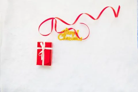 Small red gift box and gold merry christmas text with red ribbon Foto stock