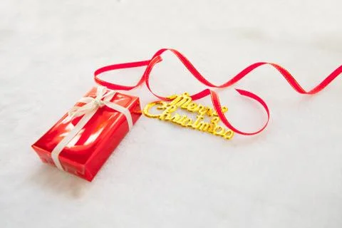 Small red gift box and gold merry christmas text with red ribbon Stock Photos