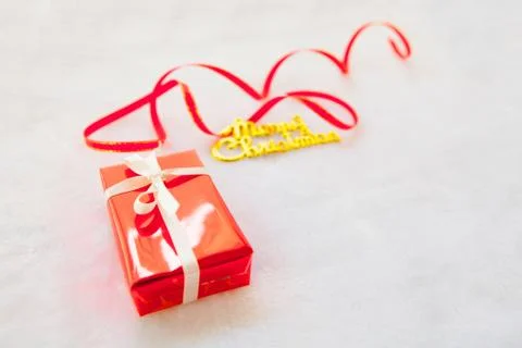 Small red gift box and gold merry christmas text with red ribbon Foto stock