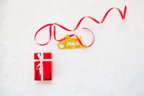 Small red gift box and gold merry christmas text with red ribbon Foto stock