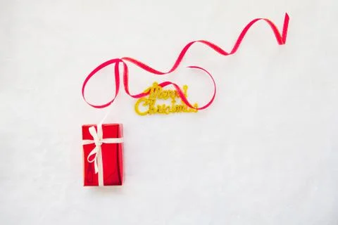 Small red gift box and gold merry christmas text with red ribbon Stock Photos