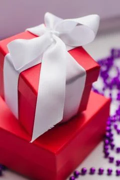 Small red gift boxes tied with a white ribbon and purple Christmas beads Foto stock