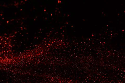 Small red glitter on dark black background Stock Photos