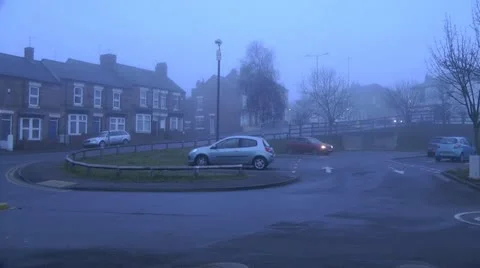 Small red hatchback car drives out of urban car park on foggy winter day Stock Footage 15102548