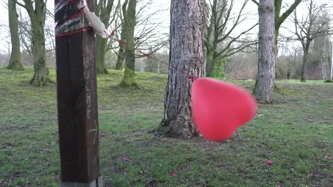 A small red heart balloon dances tied in the stormy wind Stock Footage 170652436