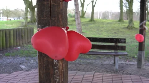 Small red heart balloons dance tied to a pole in the wind Stock Footage 170654364