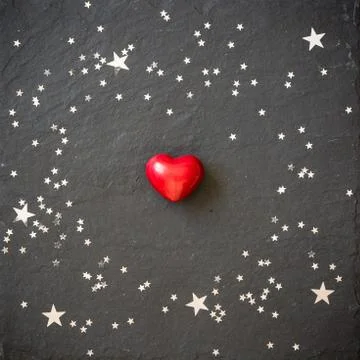 Small red heart on the black background with silver stars. Hearts and stars Stock Photos
