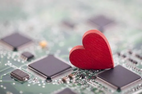 Small red heart on computer circuit board. Internet dating concept. Stock Photos