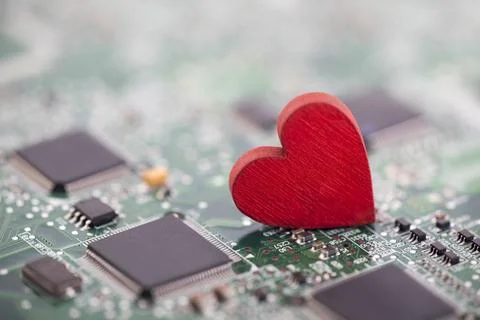 Small red heart on computer circuit board. Internet dating concept. Stock Photos