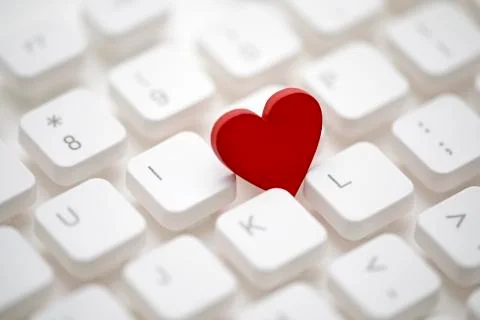 Small red heart on computer keyboard. Internet dating concept. Stock Photos
