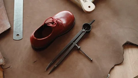 Small Red Leather Shoe and Metal Dividers on Shoemaker Pattern Bench Stock Footage 343975717