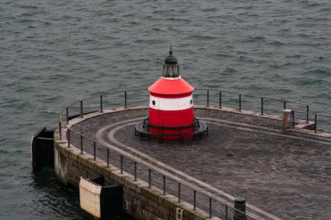 Small red lighthouse at the on of a pier. Stock Photos