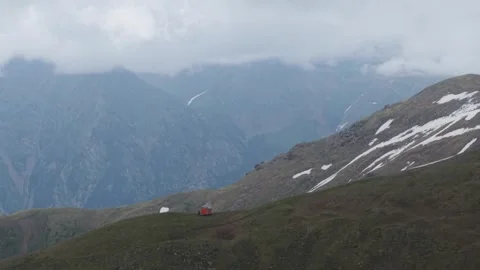 Small red mountain hut on a grassy alpine ridge Stock Footage 345387510