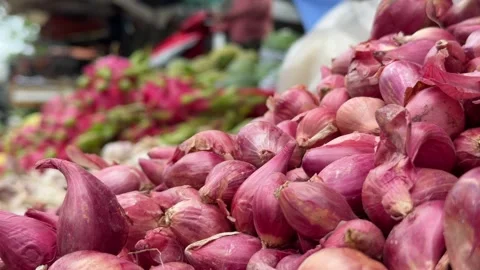 Small red onions are spread across a vendor stall, with surrounding vegetable 库存影片 329298555