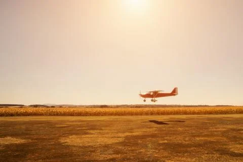 Small red plane in low pass over airstrip Stock Photos