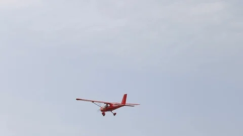 Small red private airplane with propeller in front is flying in light blue sky. Video stock 120868199