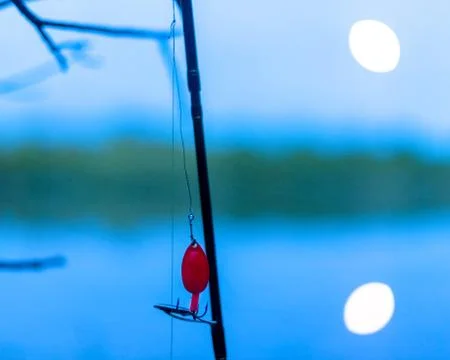 A small red spinner spinner attached to a fishing rod. Stock Photos