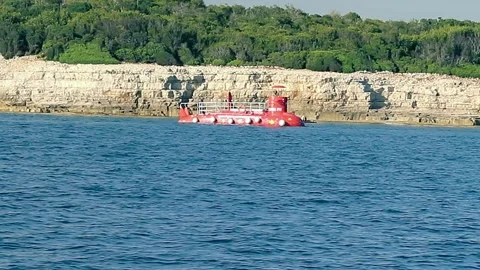 Small Red Submarine Sails Into Sea Clear Weather. Kayak With A Man Behind Boat. Stock Footage 242705502