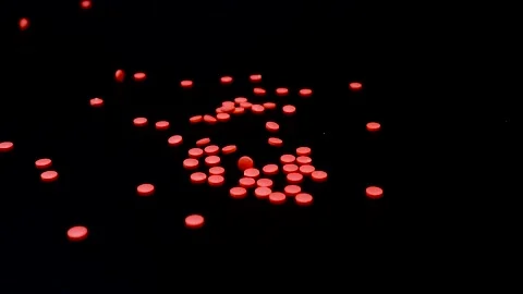 Small red tablets falling on a black surface in slow motion Video stock 147550466