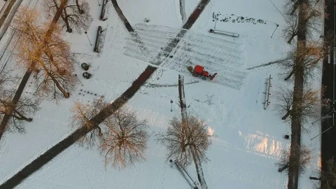 Small red tractor cleaning  fresh snow from city square, aerial Stock Footage 103468798