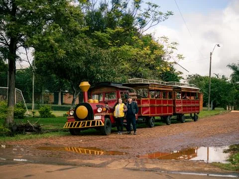 Small red train with a yellow front sits on a muddy dirt path Stock-Fotos