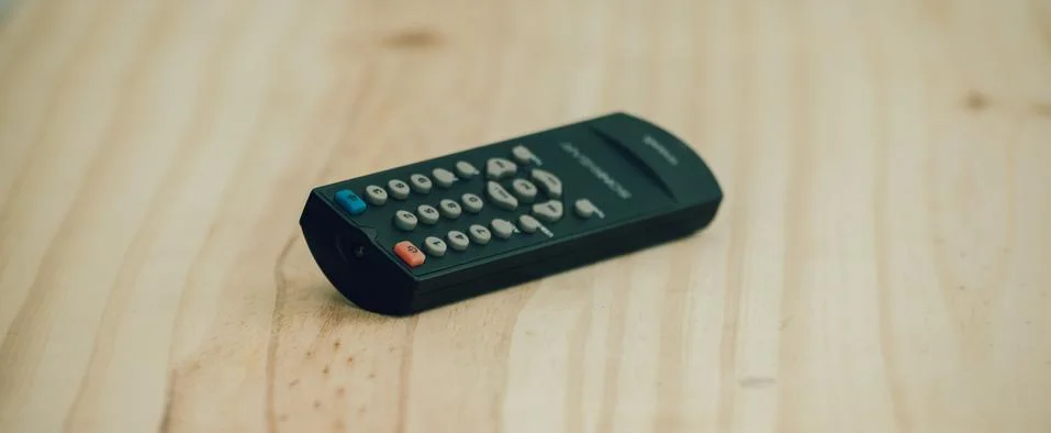 Small Remote controller lay flat on a wooden surface close up photograph. Stock Photos