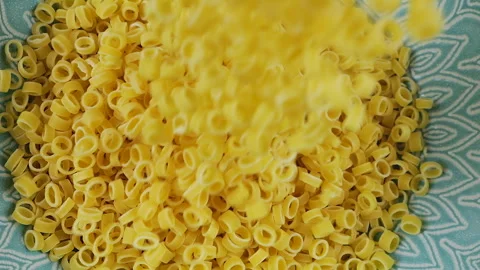 Small ring-shaped pasta is poured into a blue ceramic bowl. Top view. Stock-Footage 304390557