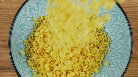 Small ring-shaped pasta is poured into a blue ceramic bowl. Stock Footage 304391232