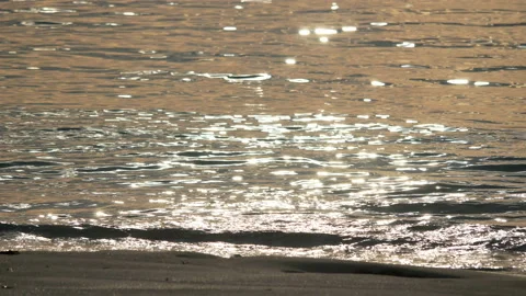 Small ripples hit sand beach with shiny sparkiling light reflections of the s Stock Footage 130584767