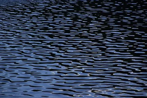 Small ripples on the water surface. Evening dusk descends on the river. Stock Photos