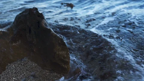 Small Ripples of Waves crash against rock Slow Motion Dusk Stock Footage 101212416