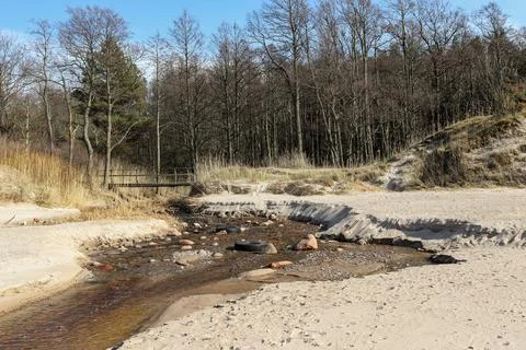 Small river in beach with bridge, sand and rocks Stock Photos