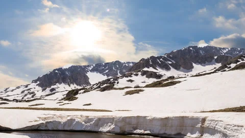 Small river flow through snowbound mountain valley at sunny day Stock Footage 315128256