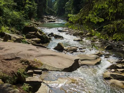 Small river flowing rapidly and vividly through its wild stony valley Stock Photos
