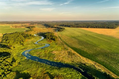 A small river flowing through meadows and agricultural fields. Aerial view Stock Photos