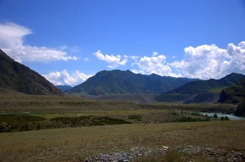 A small river flowing through a mountain valley at the foot of high hills. Stock Photos