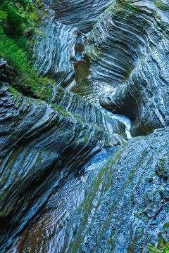 A small river flows through a rocky gorge studded with bluish-gray rocks an.. Stock Photos