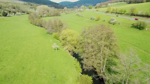 A small river flows through a valley with a forest Stock Footage 154368474