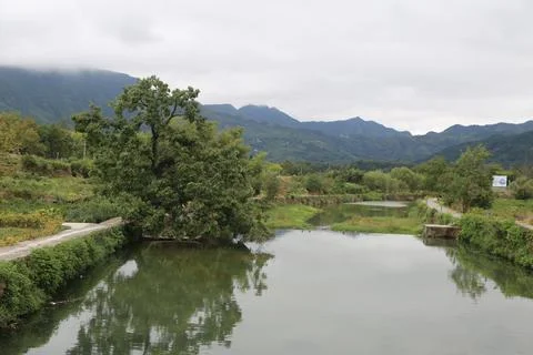 A small river flows through the valley, with green vegetation on both sides.. Stock Photos